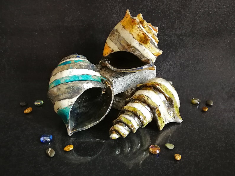 Set di conchiglie in ceramica Raku con smalto craquelé. Aggiungono un tocco costiero ed elegante alla tua casa.
Set of Raku ceramic shells with crackled glaze. Add a coastal and elegant touch to your home.