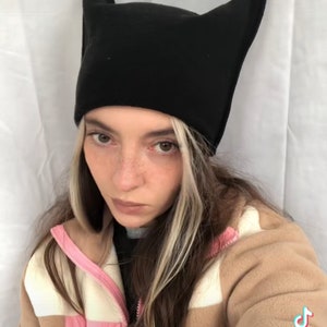 May include: A black beanie-style hat with pointed ears. The hat is worn by a person wearing a tan and pink jacket. The TikTok logo and username @rosebrownlangtry are visible in the bottom right corner.