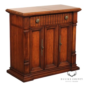 May include: A wooden cabinet with a warm brown finish. It features a single drawer with a decorative knob and three doors with ornate handles. The cabinet has a rectangular shape and is likely used for storage.