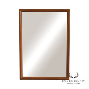May include: A rectangular mirror with a simple, brown wooden frame.