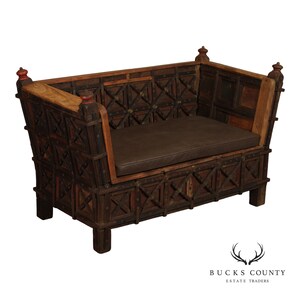 May include: A dark brown wooden bench featuring a geometric lattice pattern on the back and sides, accented with small metal studs. The bench includes a flat, rectangular seat cushion in a solid dark brown color and four sturdy legs.