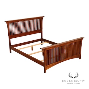 May include: A medium-brown wooden bed frame featuring a tall headboard and a shorter footboard, both constructed with vertical slats. The frame includes side rails and light-colored wooden support slats across the center of the structure.