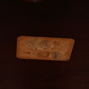 May include: A brown paper tag with handwritten text that reads "11-84 E81".