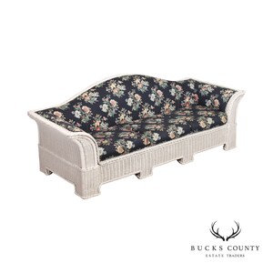 May include: White wicker sofa with a floral patterned cushion. The sofa has a curved back and a white painted finish.