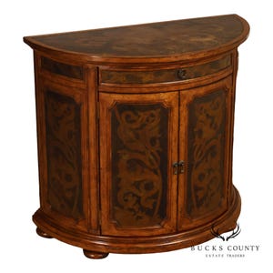 May include: A semi-circular wooden cabinet featuring a light brown finish with dark brown scrollwork patterns on the top surface, drawer front, and two cabinet doors. The piece includes a single drawer with a small circular pull and two doors.