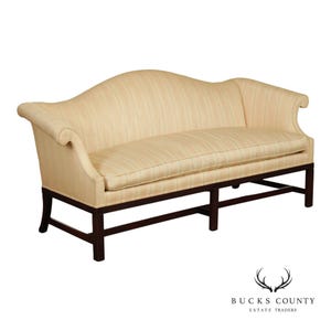 May include: A three-seat sofa upholstered in a light cream and beige striped fabric. The sofa features a curved backrest, rolled arms, and a single long seat cushion. It is supported by a dark brown wooden frame with straight legs and stretchers.