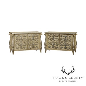 May include: Pair of ornate, carved wooden cabinets with silver accents. Each cabinet has two doors and sits on four legs. The cabinets are painted a light cream color.