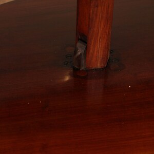 May include: A two-tiered wooden table with a dark brown finish. The table has a round top and a scalloped edge. The bottom tier is slightly smaller than the top tier. The table is supported by a single, sturdy wooden post.