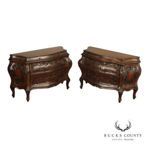 May include: A pair of matching dark brown wooden chests, each featuring a curved front, two drawers, and intricate floral carvings on the drawer fronts and sides. The chests stand on four cabriole legs and have a smooth, polished top surface.