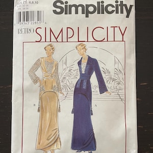 May include: A Simplicity 8640 sewing pattern envelope featuring illustrations of two floor-length gowns. One gown is gold with lace sleeves, and the other is dark blue with a lace bodice. The text includes Simplicity, Retro Simplicity, and size H 6,8,10.
