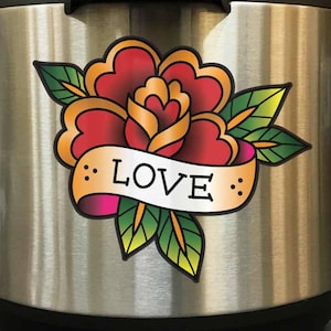 May include: A stainless steel Instant Pot with a colorful sticker of a red rose with green leaves and a banner that says "LOVE".