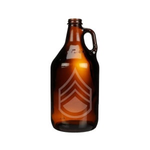 May include: A brown glass growler with a handle and a military rank insignia etched on the front. The growler is empty and has a wide mouth for filling. The glass has a slight amber tint.