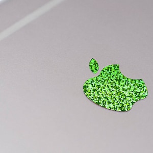 May include: A green glitter apple logo on a light gray background.