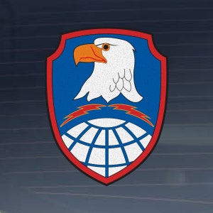 May include: A blue and red shield with a white eagle head with a yellow beak and eyes. The eagle is facing left and has a white and grey body. The shield has a white globe with red lightning bolts above it.