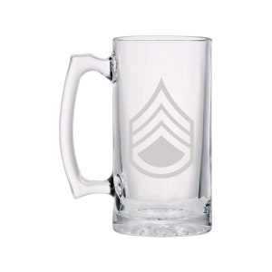 May include: A clear glass beer mug with a handle. The mug has a white etched design of a military rank insignia, a Sergeant's chevron.