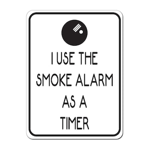 May include: A white sign with a black border and a black and white illustration of a smoke alarm. The sign reads "I use the smoke alarm as a timer."