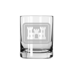Puede incluir: Un vaso de vidrio transparente con un diseño grabado en blanco de un castillo. El castillo está dentro de un marco cuadrado.