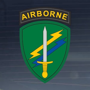 May include: A green and yellow military patch with the word "AIRBORNE" in yellow letters on a black background. The patch features a silver sword with a yellow handle and two lightning bolts, one yellow and one blue.
