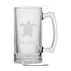 Puede incluir: Una jarra de cerveza de vidrio transparente con asa. La jarra tiene un diseño grabado de una tortuga marina y las palabras "Outer Banks".