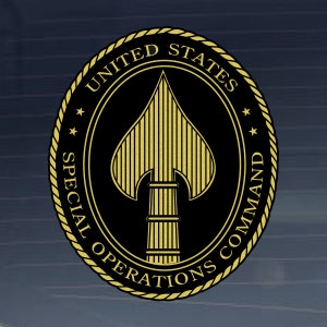 May include: A gold seal with a black background and the text "UNITED STATES SPECIAL OPERATIONS COMMAND" around the edge. A gold spearhead is in the center.