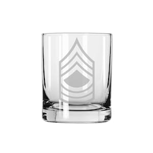 May include: A clear glass tumbler with an etched design of a military rank insignia. The insignia features five chevrons and a diamond shape, indicating the rank of Sergeant First Class.