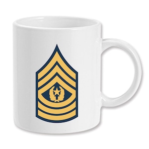 Puede incluir: Taza de café de cerámica blanca con un distintivo de rango militar dorado y azul. El distintivo tiene cinco rayas doradas y una estrella azul con una corona.