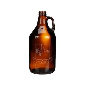 May include: A brown glass growler with a handle. The growler has an etched design of a bird's foot and the word "STRIKE" on a banner.