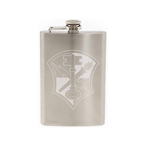 May include: A silver stainless steel flask with an engraved design of a shield with a key, lightning bolt, and torch.