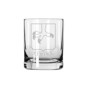 May include: A clear glass tumbler with an etched design of a bird's claw and the word "STRIKE" on a banner.
