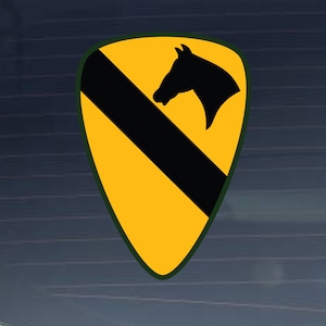 May include: A yellow and black military patch with a horse head silhouette. The patch is shaped like a triangle with a black diagonal stripe.