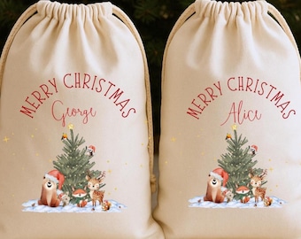 May include: Two beige drawstring Christmas gift bags. Each bag has the words "MERRY CHRISTMAS" in red script, with a name below. A Christmas tree and woodland creatures are printed on the front.