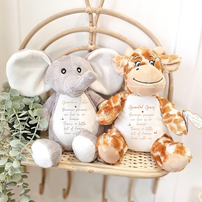 May include: Two plush stuffed animals, a gray elephant and a brown giraffe, with embroidered messages. The elephant says "Grandma Julie Because someone we love is in heaven There's a little bit of heaven here with us." The giraffe says "Grandad Gary Because someone we love is in heaven There's a little bit of heaven here with us."