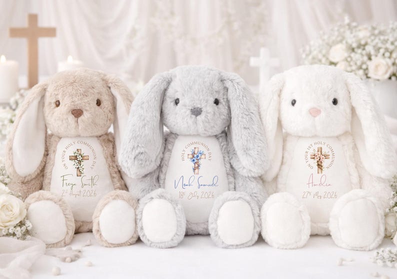 May include: Three plush stuffed bunnies in beige, gray, and white, each featuring a white belly patch printed with a cross graphic, the text "On Your Holy Communion Day," and personalized names and dates in various colors and script fonts.