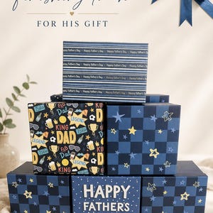 Op de afbeelding: Een verzameling vierkante geschenkdozen in marineblauw en zwart, voorzien van patronen met gele sterren, bierpullen, zonnebrillen en teksten zoals "Happy Father's Day", "King", "Legend" en "Fab Dad", afgewerkt met een donkerblauwe strik.