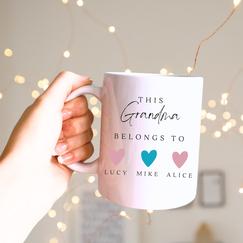 May include: White ceramic mug with the text "This Grandma Belongs To" and three hearts with the names Lucy, Mike, and Alice printed below.