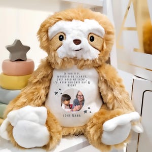 Könnte beinhalten: Ein Plüschtier-Faultier mit braunem Fell und weißem Gesicht. Das Faultier hat einen weißen Bauch mit einem Foto eines Kindes und eines Erwachsenen. Auf dem Bauch steht "IF YOU FEEL WORRIED OR SCARED, JUST HOLD ME TIGHT, I'LL KEEP YOU SAFE DAY & NIGHT. LOVE NANA."