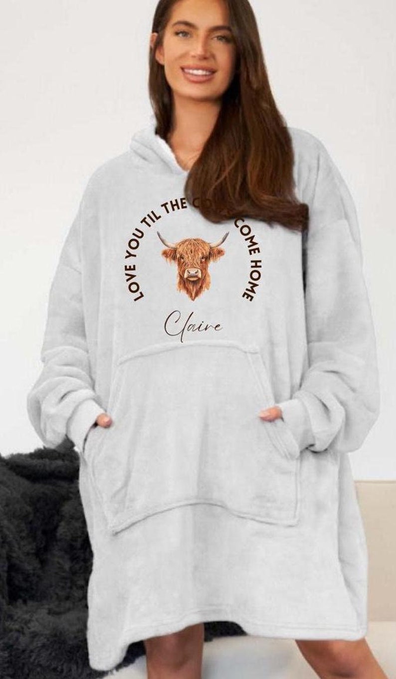 May include: A white hooded sweatshirt with a brown Highland cow illustration and the text "Love you til the cows come home" and the name "Claire" printed on the front.