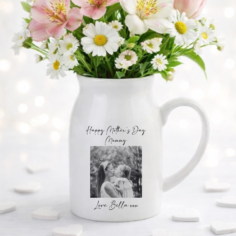 May include: White ceramic pitcher with a handle, filled with a bouquet of pink and white flowers. The pitcher has a black and white photo and the text "Happy Mother's Day Mummy, Love Bella xxx."