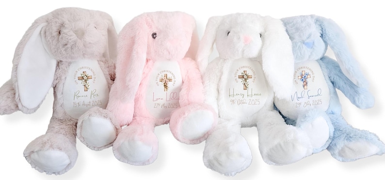 Op de afbeelding: Vier pluche konijnen in pastelkleuren: grijs, roze, wit en blauw. Elk konijn heeft lange oren, een witte buik en een kruisontwerp met gepersonaliseerde tekst. Deze knuffelige konijnen zijn perfect voor een baby of kind.