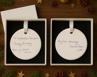 May include: Two white, round ornaments with handwritten messages in black ink, presented in square gift boxes. One reads "To My Beautiful Daughters, Happy Birthday, Love you forever Mum." The other says "My love always, Nanna Joan xOX."