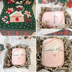 May include: A pink marble mug with the text "Francis's Mummy" and a heart. The mug is in a white gift box with brown shredded paper.