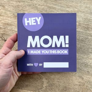 May include: Purple book with the text "HEY MOM! I MADE YOU THIS BOOK WITH ♥ BY" and a blank space to fill in the name.