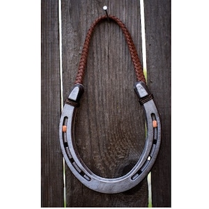 Steel genuine  hanging lucky horseshoe decor with braided leather hanger.