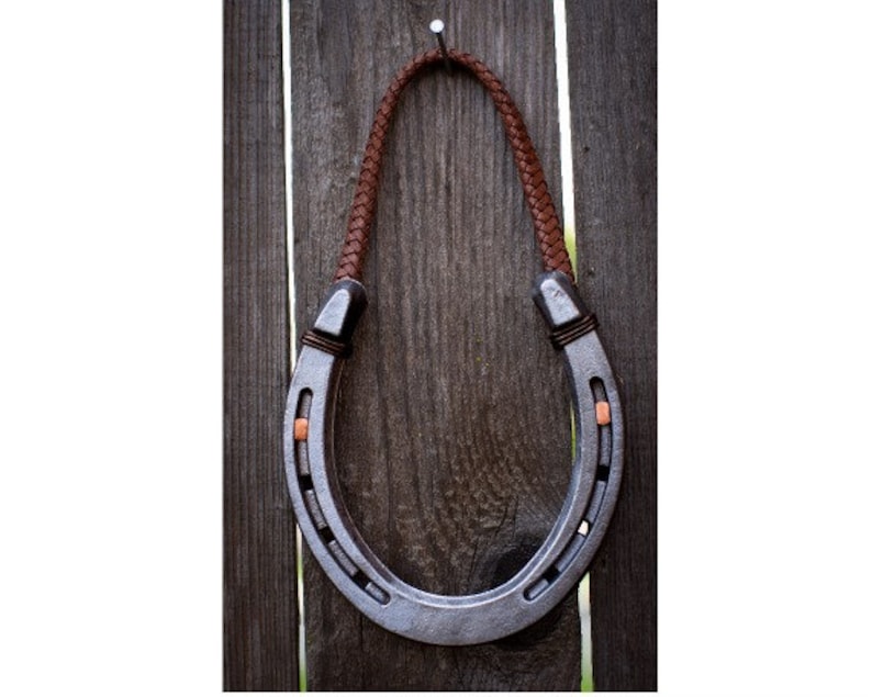 Steel genuine  hanging lucky horseshoe decor with braided leather hanger.