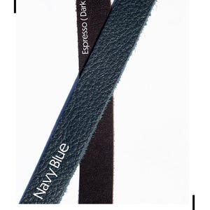 May include: Image showcasing leather color options. The text "Leather Choices" is at the top. Two leather swatches are displayed: one in a dark brown, smooth finish, and the other in navy blue with a slight pebble grain. The text "Navy Blue" is on the navy swatch.