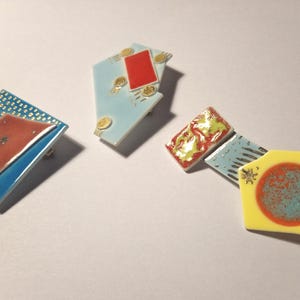 3 Colourful ceramic brooches, each one querky, alumina substrate, blue/yellow/red/maroon/pale blue glaze + lustres