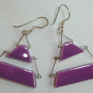 May include: A pair of purple glass earrings with a triangular and rectangular shape. The earrings are suspended from silver hooks.