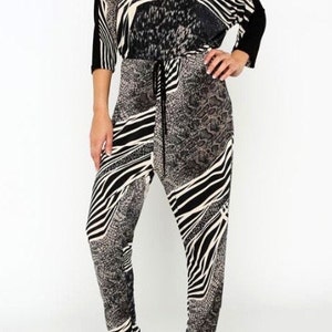May include: A black and white zebra print jumpsuit with a drawstring waist. The jumpsuit has a v-neck and 3/4 sleeves.