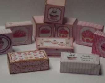 Könnte beinhalten: Eine Sammlung von rosa und weißen Schachteln mit Cupcake-Designs. Die Schachteln sind mit verschiedenen Cupcake-Bildern und dem Text "Sprinkle Cupcake Box Cup Cake Kitchen" verziert.