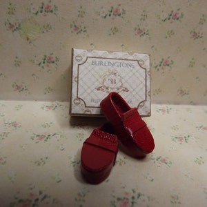 May include: Two red leather loafers with a box that says "Burlintgton's" on it.